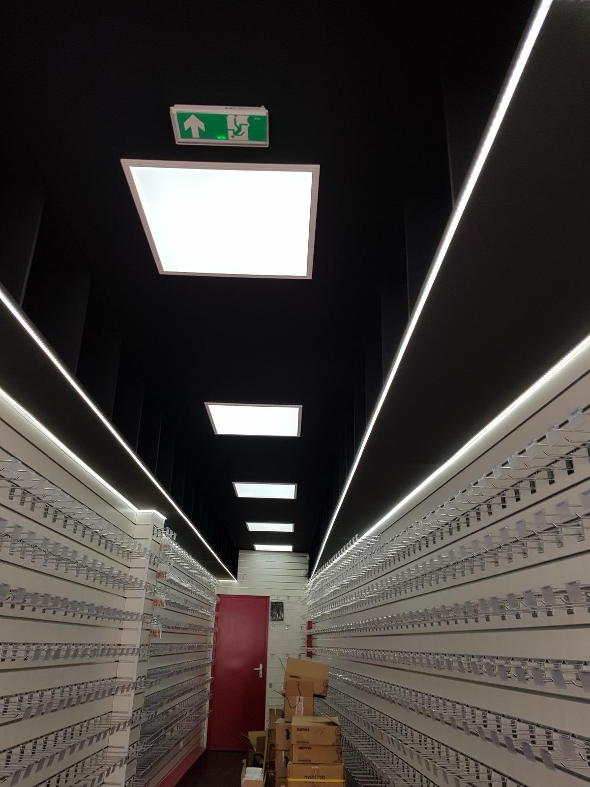 Plafond noir avec lignes LED intégrées dans un espace retail parisien
